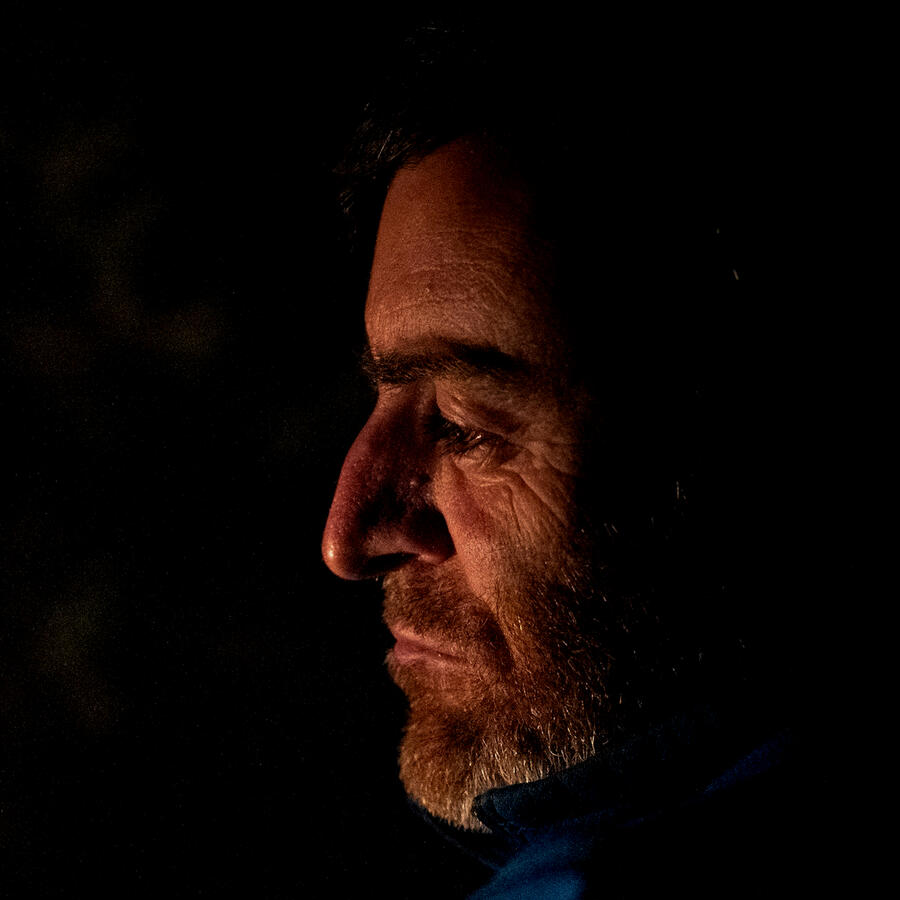 Image of a man staring into a fire, conveying the process of a faith transition or faith expansion.